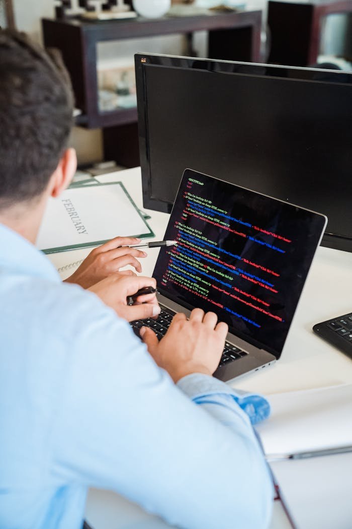 Offerings An office worker intensely typing code on a laptop, showcasing programming skills.